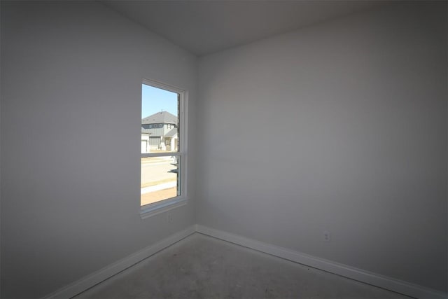 spare room featuring baseboards, plenty of natural light, and unfinished concrete floors