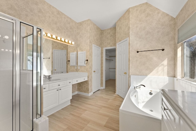 full bath featuring a spacious closet, a shower stall, a whirlpool tub, wood finished floors, and vanity