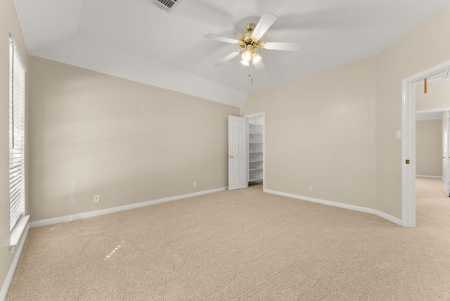 spare room featuring baseboards, attic access, vaulted ceiling, light carpet, and a ceiling fan