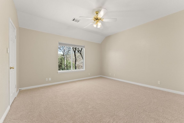 spare room with visible vents, ceiling fan, baseboards, lofted ceiling, and light carpet