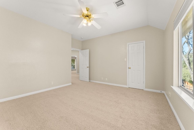 empty room with a wealth of natural light, visible vents, baseboards, and light colored carpet