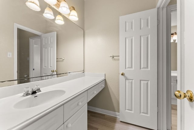 bathroom featuring baseboards, wood finished floors, and vanity