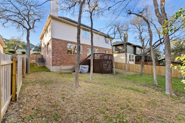 rear view of property featuring brick siding, central AC unit, a lawn, a chimney, and a fenced backyard