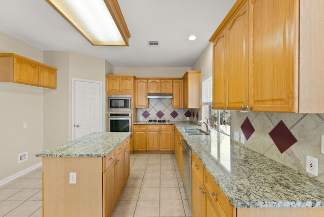 kitchen with a center island, light tile patterned floors, light stone counters, stainless steel appliances, and a sink