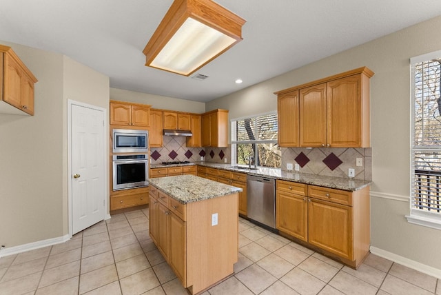 kitchen with tasteful backsplash, visible vents, a center island, light stone countertops, and stainless steel appliances