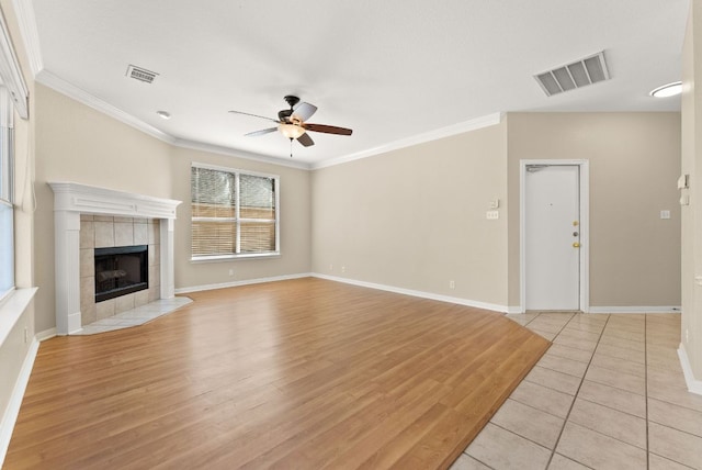 unfurnished living room with visible vents, crown molding, ceiling fan, light wood-style flooring, and a tile fireplace