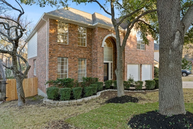 traditional home with brick siding, an attached garage, and fence