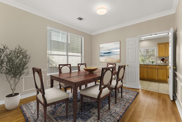 dining room with light wood-style flooring, visible vents, and ornamental molding