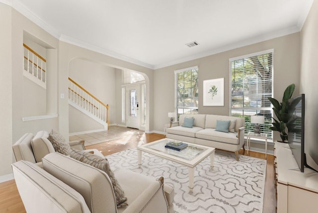 living room with stairway, baseboards, light wood finished floors, and ornamental molding