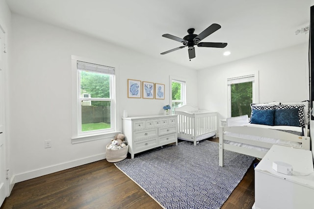 bedroom with a ceiling fan, baseboards, recessed lighting, dark wood-style flooring, and a crib