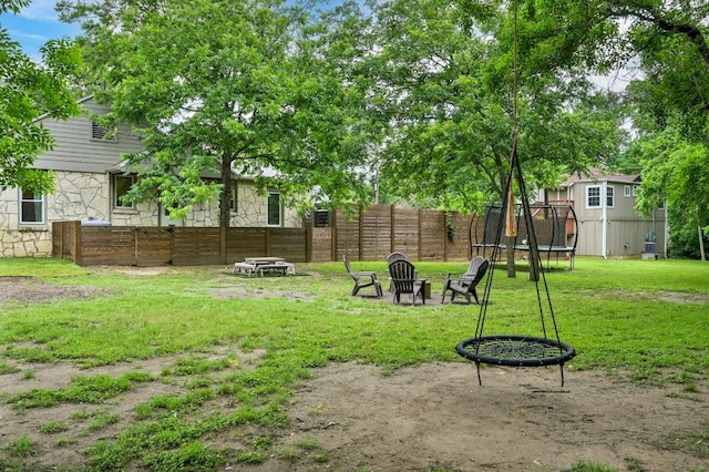 view of yard featuring a fire pit, a trampoline, and fence private yard