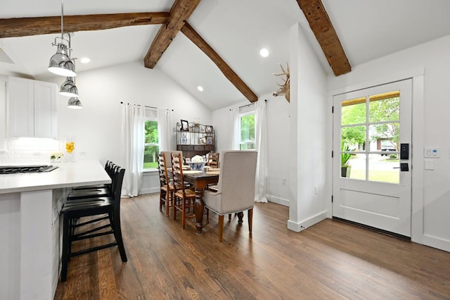 dining space featuring dark wood-type flooring, lofted ceiling with beams, a healthy amount of sunlight, and baseboards