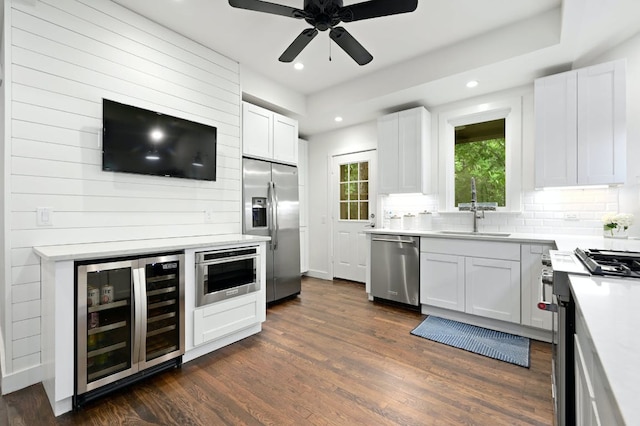 kitchen with a sink, appliances with stainless steel finishes, beverage cooler, and dark wood finished floors