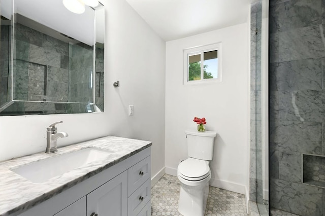 bathroom featuring vanity, toilet, baseboards, and a tile shower