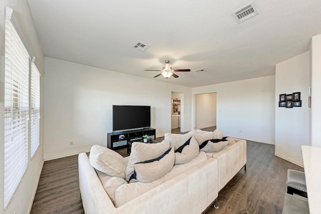 living room with dark wood-type flooring, a ceiling fan, and visible vents