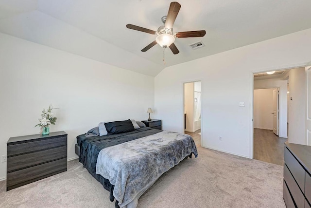 bedroom featuring a ceiling fan, visible vents, ensuite bath, vaulted ceiling, and light carpet