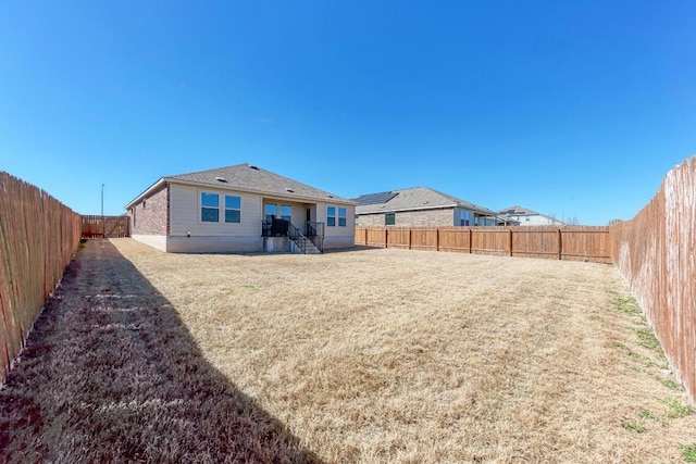 back of house featuring a lawn and a fenced backyard