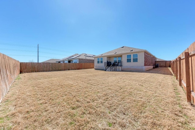 back of house with a lawn and a fenced backyard