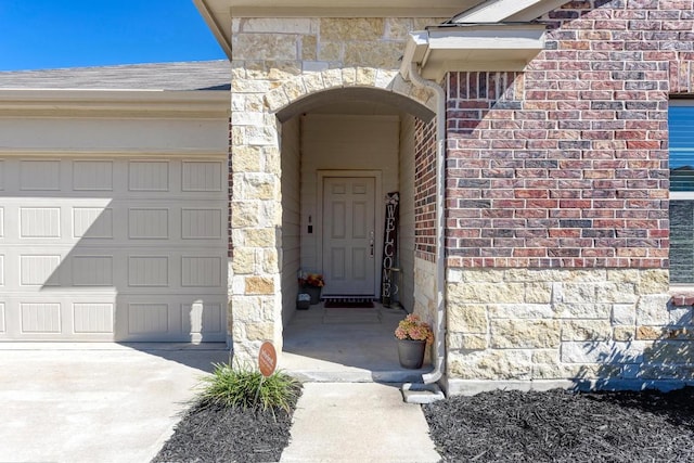 property entrance featuring a garage, stone siding, brick siding, and roof with shingles