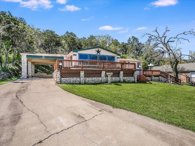 view of front facade featuring a carport, driveway, a wooden deck, and a front yard