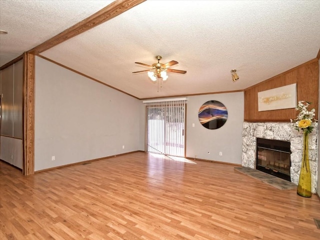 unfurnished living room featuring a stone fireplace, lofted ceiling, light wood-style floors, and a textured ceiling