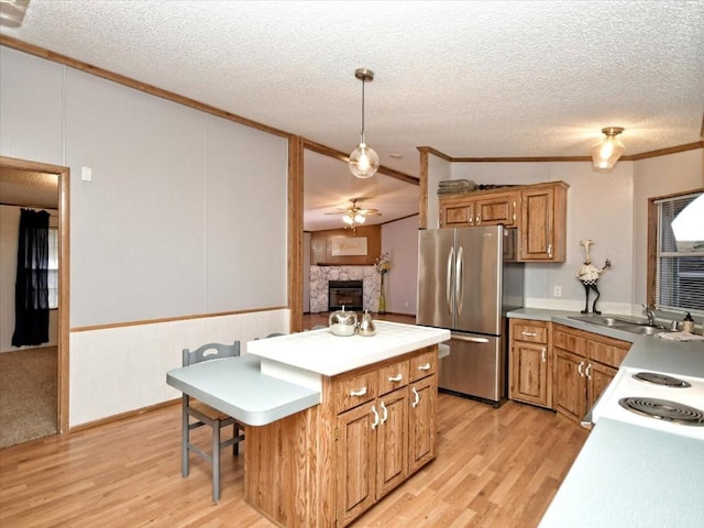 kitchen with a sink, light wood-style floors, freestanding refrigerator, and ornamental molding