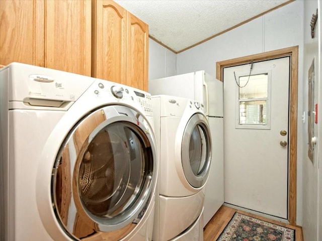 laundry room featuring crown molding, light wood-style flooring, washer and dryer, cabinet space, and a textured ceiling