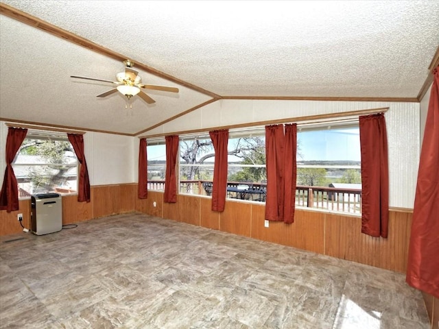 unfurnished room featuring wooden walls, wainscoting, vaulted ceiling, a textured ceiling, and carpet flooring