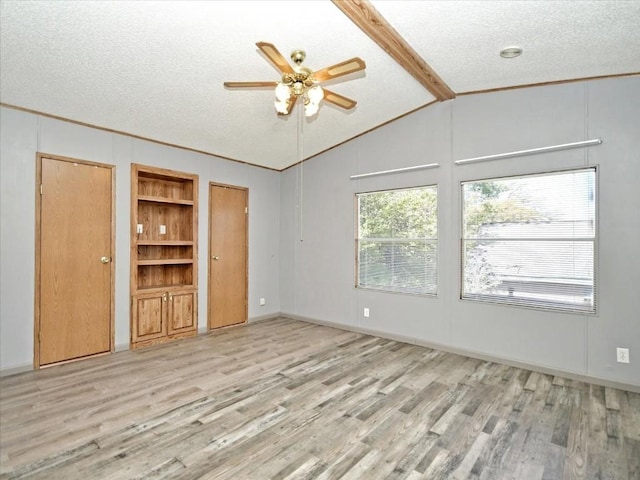 unfurnished room with lofted ceiling with beams, wood finished floors, and a textured ceiling