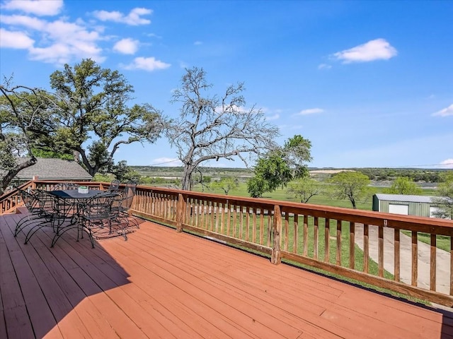 deck with an outbuilding, outdoor dining space, and a storage unit