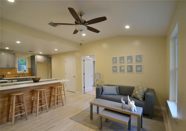 living area featuring baseboards, ceiling fan, lofted ceiling, recessed lighting, and light wood-style floors