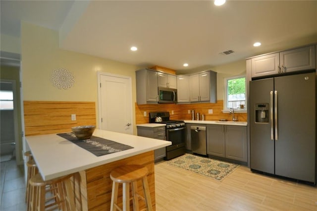 kitchen with a sink, visible vents, appliances with stainless steel finishes, and gray cabinetry