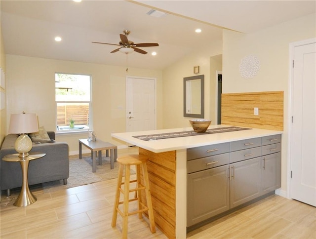 kitchen with recessed lighting, a breakfast bar, gray cabinets, and light countertops