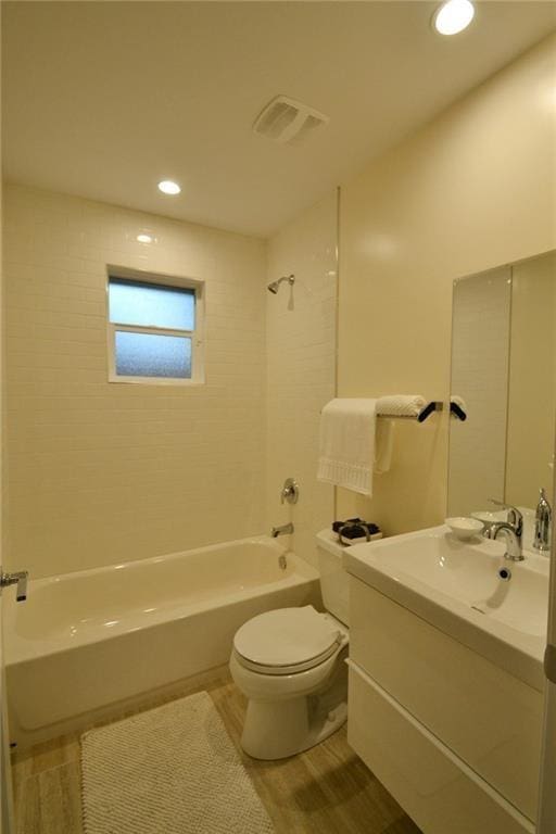 bathroom featuring vanity, wood finished floors, visible vents, shower / tub combination, and toilet