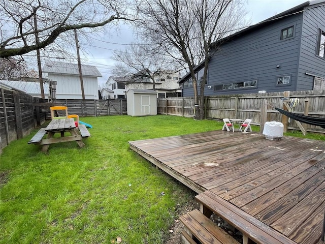 view of yard featuring a fenced backyard, a wooden deck, a storage unit, and an outdoor structure