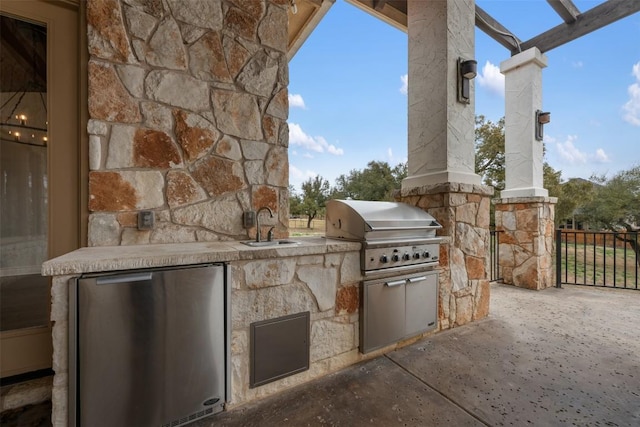 view of patio with an outdoor kitchen, a grill, fence, and a sink