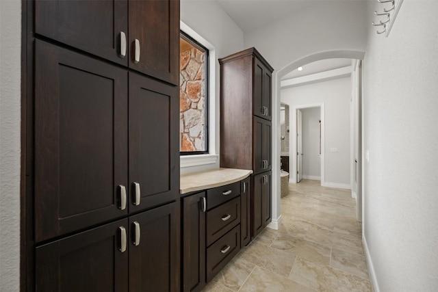 hallway with arched walkways and baseboards