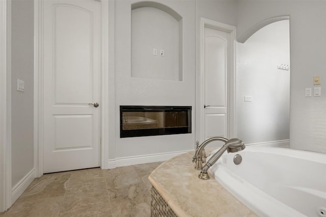 full bathroom with a glass covered fireplace and a bath