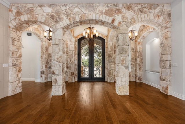 foyer entrance with wood finished floors, french doors, and arched walkways