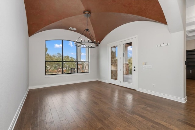 spare room with visible vents, baseboards, lofted ceiling, dark wood-type flooring, and a chandelier