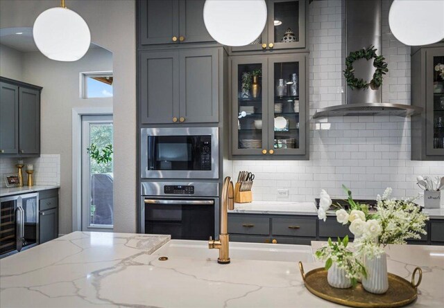 kitchen with oven, gray cabinets, glass insert cabinets, built in microwave, and light stone countertops