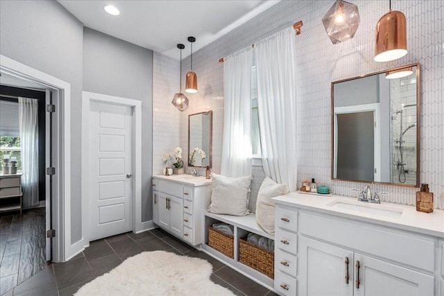 bathroom featuring a sink, baseboards, two vanities, and tile patterned floors