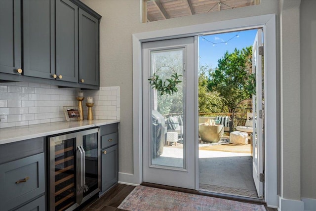 doorway featuring baseboards, dark wood-type flooring, a bar, and beverage cooler