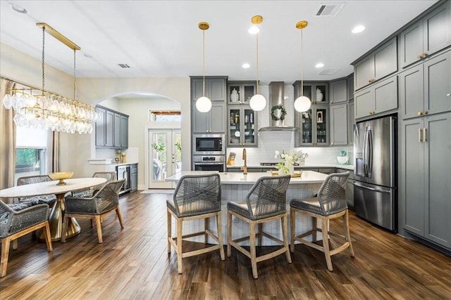 kitchen featuring decorative backsplash, wall chimney exhaust hood, visible vents, and stainless steel appliances