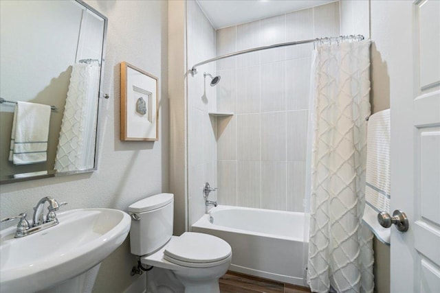 full bathroom with toilet, a textured wall, shower / tub combo, wood finished floors, and a sink