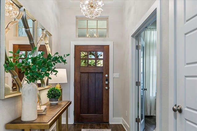 entryway with baseboards, an inviting chandelier, and dark wood finished floors