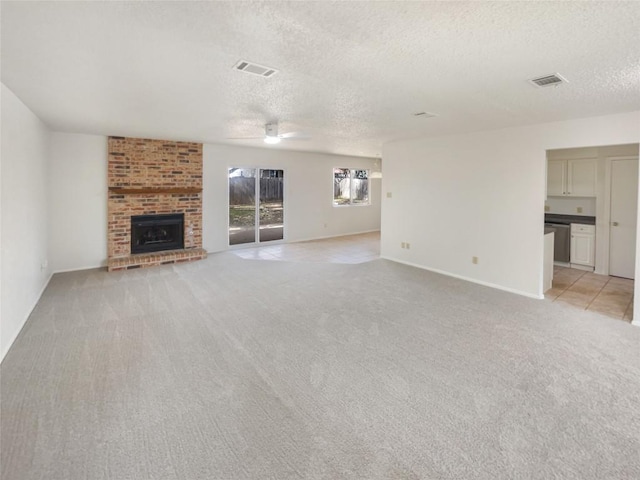 unfurnished living room featuring visible vents, light carpet, a textured ceiling, and a fireplace