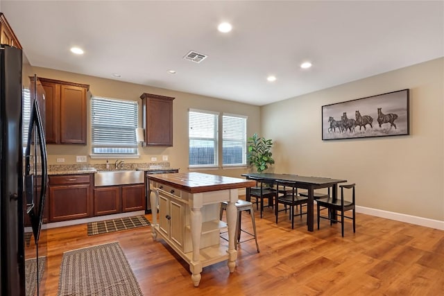 kitchen with visible vents, black fridge, a sink, recessed lighting, and light wood-style floors