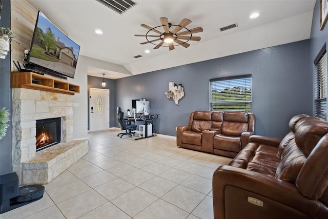 living area featuring a stone fireplace, light tile patterned flooring, a ceiling fan, and visible vents