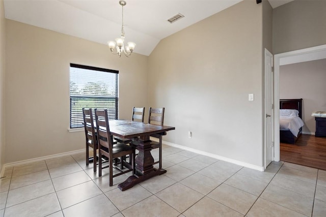 dining area with visible vents, a notable chandelier, light tile patterned floors, baseboards, and vaulted ceiling